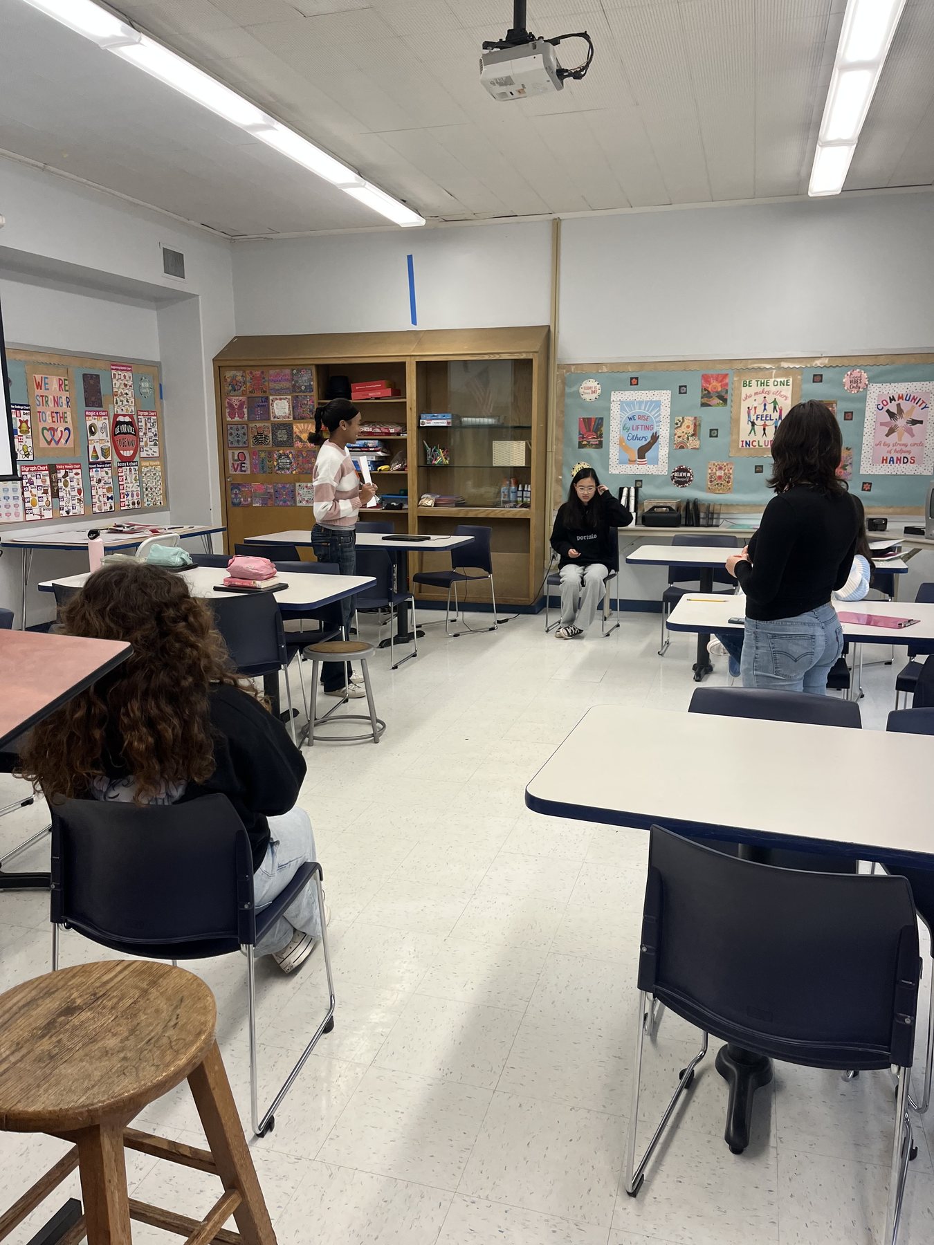 BridgED students working together in a classroom under posters about inclusion and community