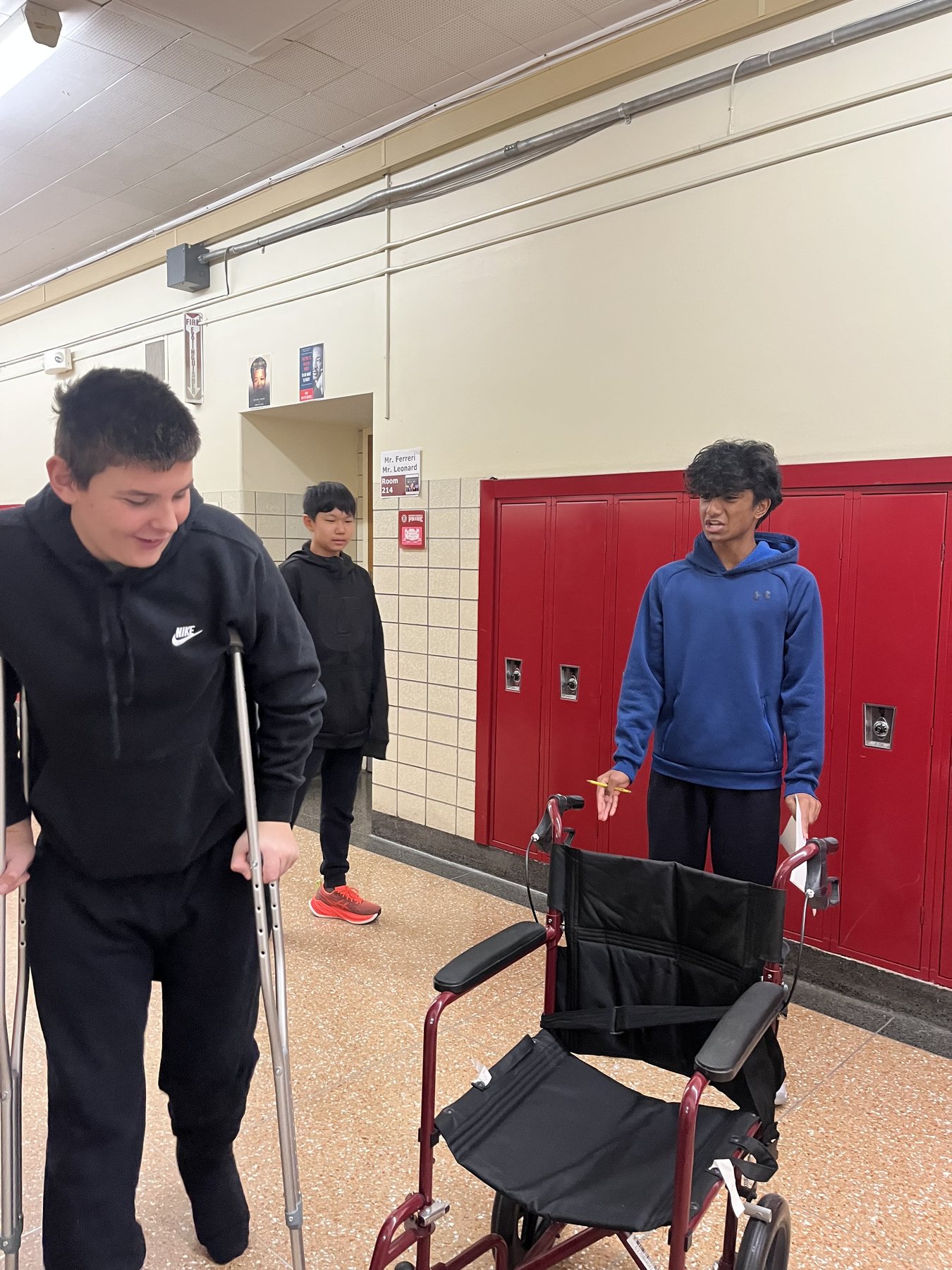 Students in a school hallway with crutches and a wheelchair during a disability awareness activity
